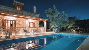 Edifici de pedra amb piscina, seients exteriors i una pèrgola.