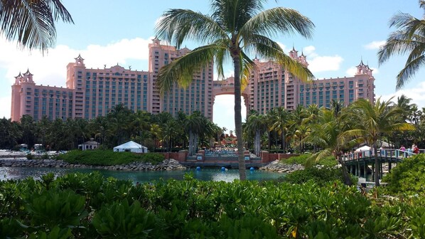 A large resort with multiple high-rise buildings, a central archway, and a pool area surrounded by palm trees.