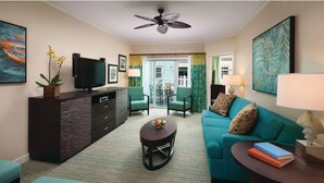 Een moderne woonkamer met een turquoise bank, een donker houten tv-meubel, een ronde salontafel en een plafondventilator.
