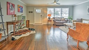 A spacious living room with hardwood floors, a ceiling fan, and a large window providing natural light.