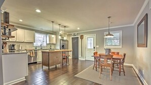 A modern kitchen with wooden cabinets, a central island, and pendant lighting.