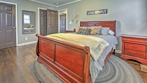 A bedroom with a wooden bed, a nightstand, a dresser, and a ceiling fan.