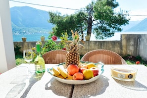 A table with a fruit bowl, a bottle of wine, and a candle. - Waterfront Apartment Petrovina (Kotor)