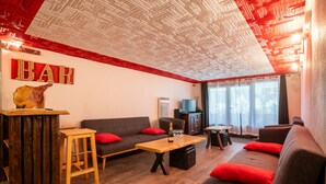 Ein modernes Wohnzimmer mit einer Holztresore, einem Sofa mit roten Kissen und einer Decke mit rotem und weißem Muster.