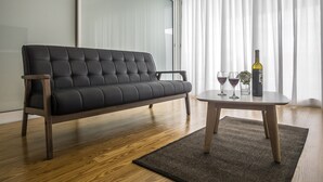 A modern living room with a black sofa, a small round table, and a bottle of wine. - Market Place C 1BR (historical city center) (Ponta Delgada)