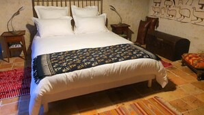 A bed with white linens and a patterned blanket, a wooden headboard, two bedside tables with lamps, a small rug, and a wall with a mural. - Les Voies Blanches (Vouvray)