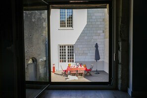 A room with a sliding glass door leading to an outdoor patio area with a table and chairs. - Les Voies Blanches (Vouvray)