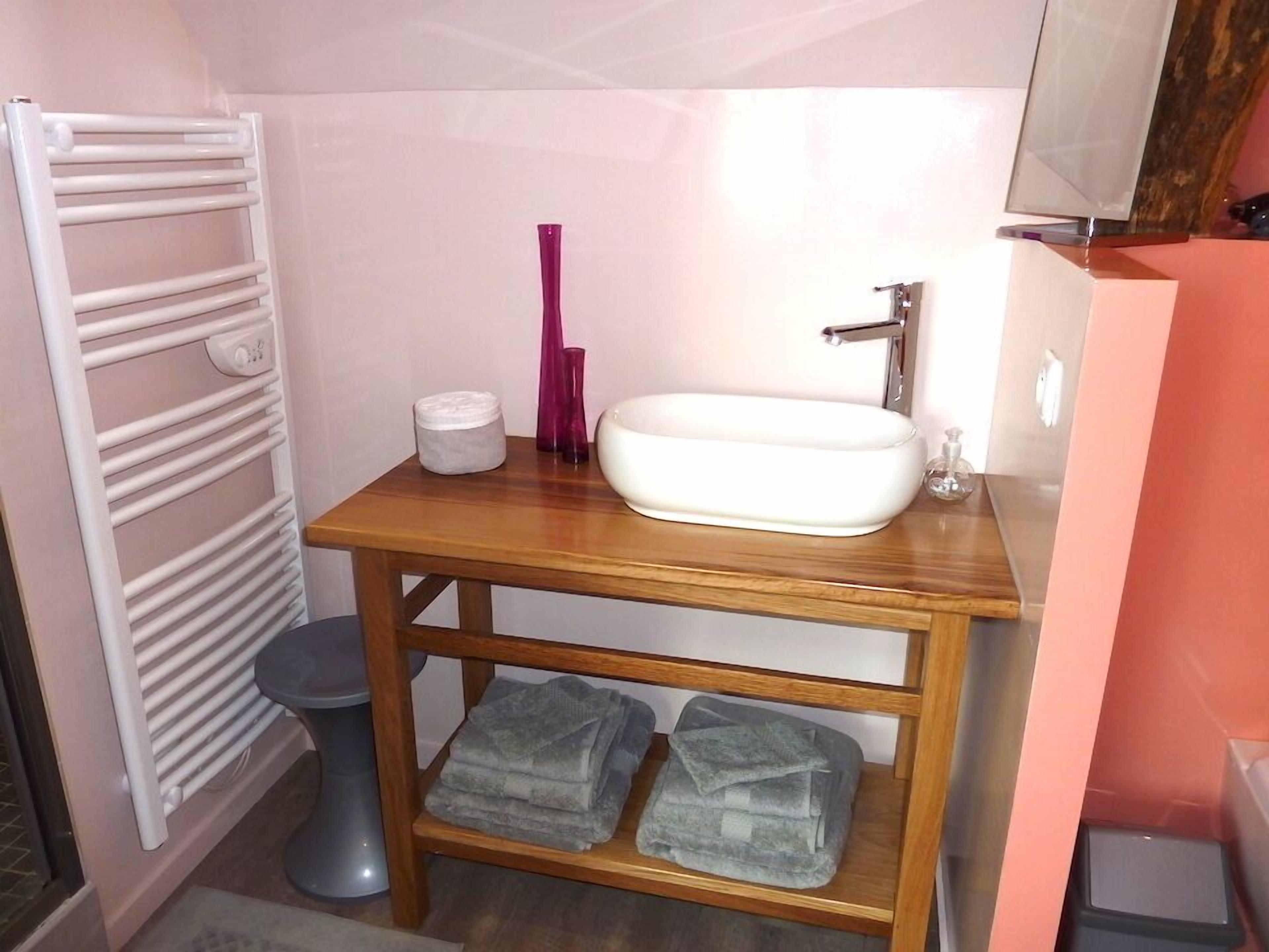 A bathroom with a white sink, wooden vanity, a towel rack, and a toilet.