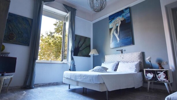 Une chambre à coucher avec un lit, une télévision et des œuvres d’art accrochées aux murs.