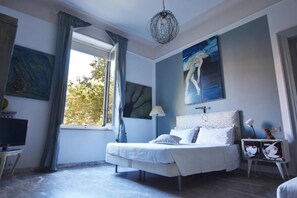 Une chambre à coucher avec un lit, une télévision et des œuvres d’art accrochées aux murs.