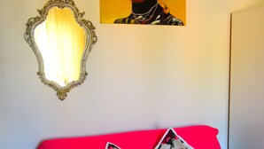 Une pièce avec un canapé rouge, un miroir et un tableau accroché au mur.