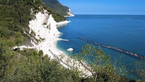 Un paysage côtier avec une plage, des falaises et de la végétation.