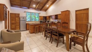 Eine Küche mit Holzausstattung, einem Kühlschrank und einem Essbereich mit Tisch und Stühlen.