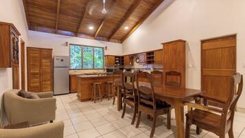 Une cuisine avec des meubles en bois, un réfrigérateur et un coin repas comprenant une table et des chaises.
