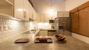 Una cocina moderna con armarios blancos, un refrigerador de acero inoxidable, un microondas y un techo de madera.