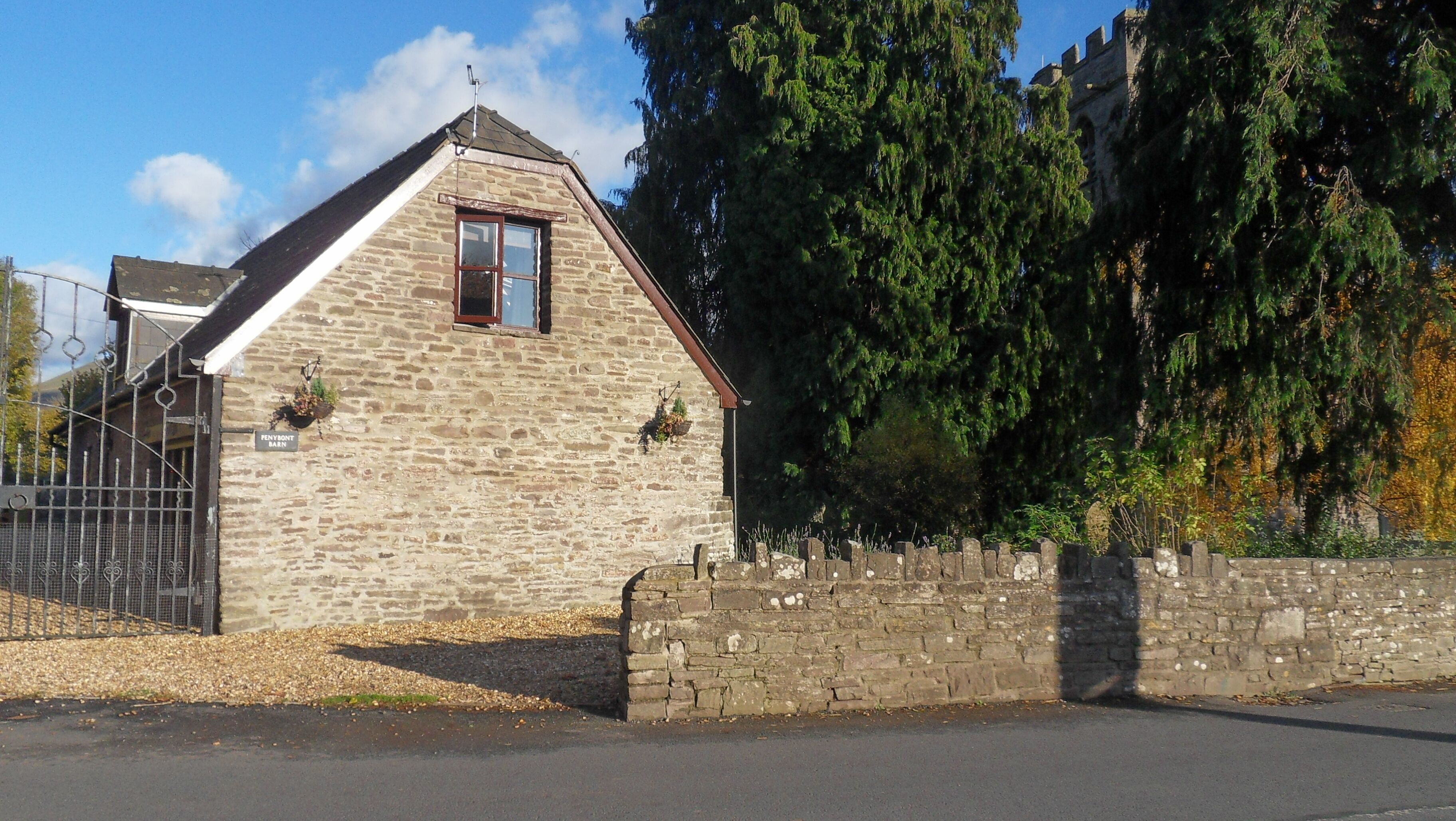 A stone building with a gabled roof, a small window, and a sign that reads "PENYSON HALL".