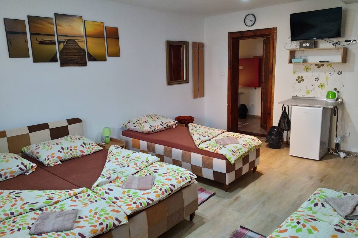 Een kamer met twee bedden, een kleine koelkast, een televisie en een klok aan de muur.