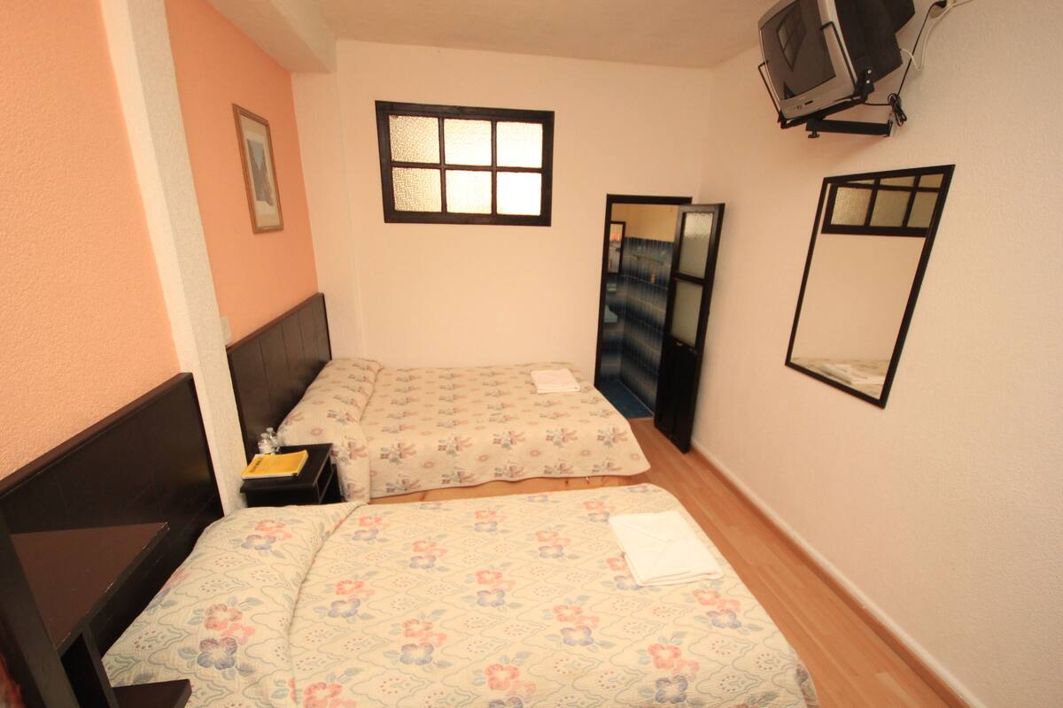 Un dormitorio con dos camas, televisión y ventana.