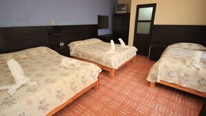 A hotel room with three beds, a television on a stand, and a mirror on the wall.