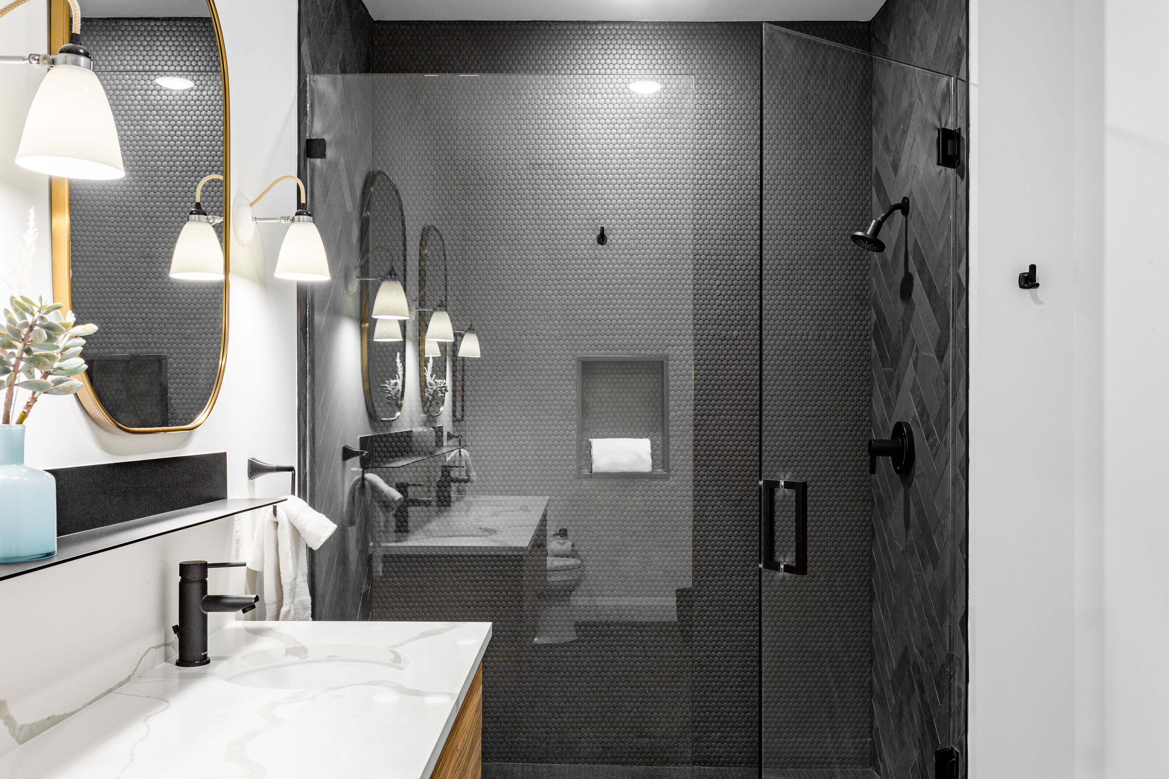 Une salle de bain moderne avec une douche à parois de verre, un grand miroir et un lavabo en marbre.