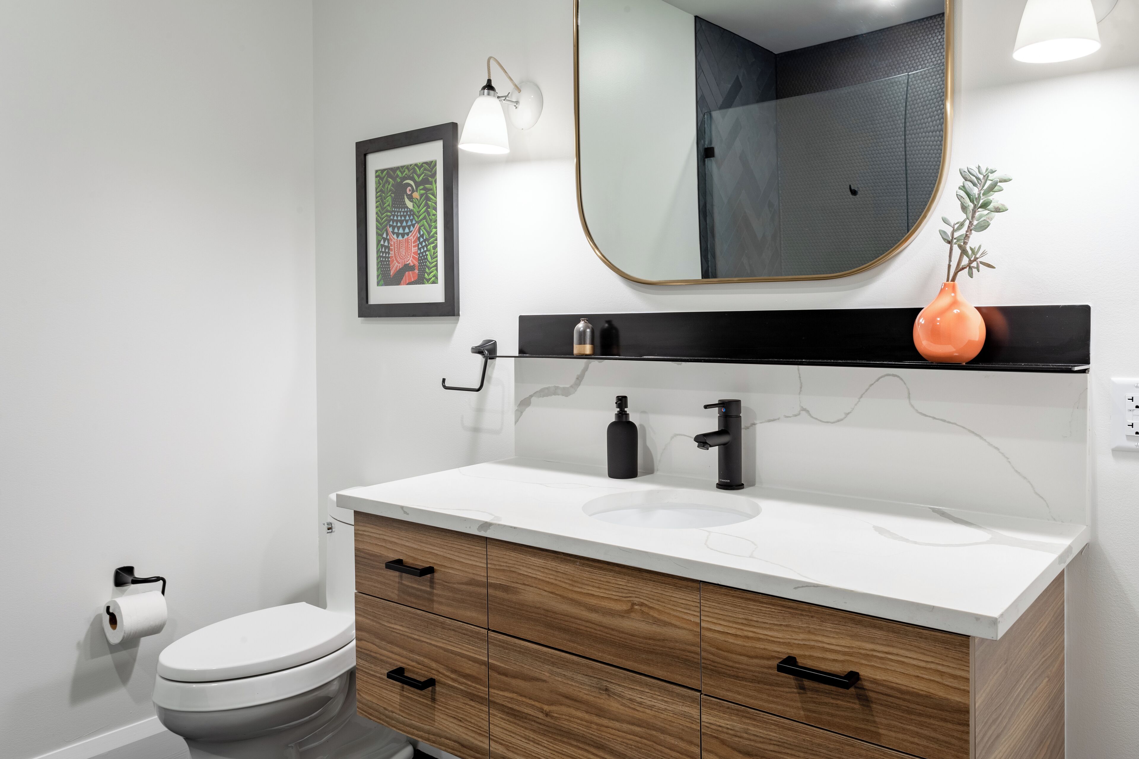 A modern bathroom with a white sink, black faucet, and wooden cabinet drawers.