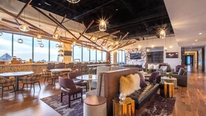 A modern hotel lobby with high ceilings, exposed beams, and a mix of seating areas including sofas and tables. - Mint House Dallas Downtown by Kasa (Dallas)