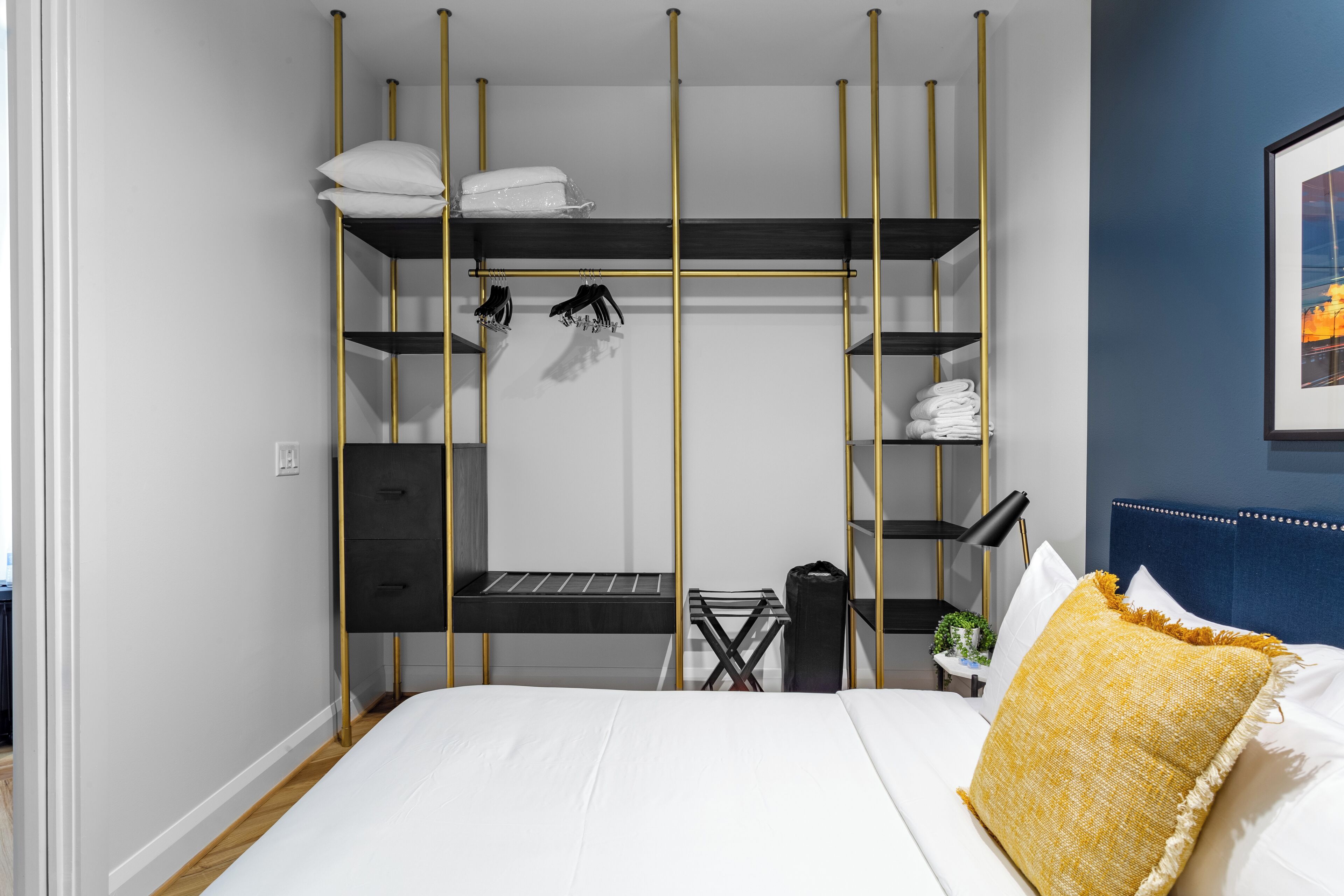 A bedroom with a bed, a wardrobe with multiple shelves, a desk, and a chair.