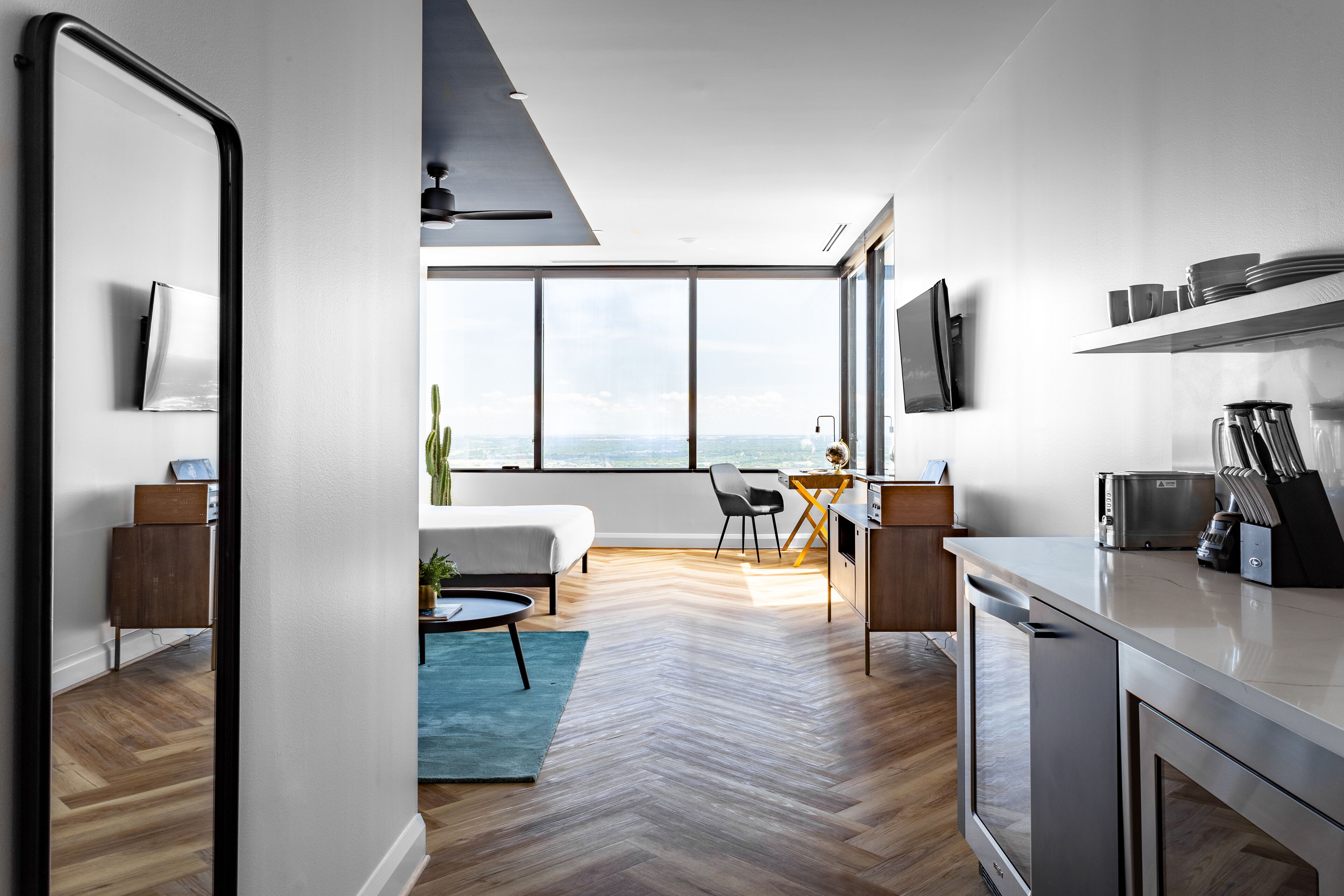 Eine moderne Wohnung mit Küche, Essbereich und einem großen Fenster mit Blick auf die Stadt.