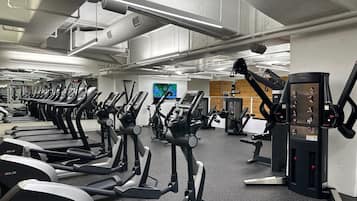 Une salle de sport équipée de plusieurs tapis de course, de vélos d’exercice et d’appareils de musculation.