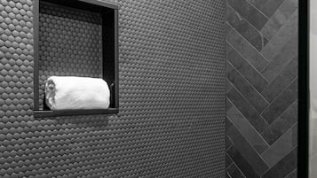 Een badkamer met een structuurwand, een handdoek in een klein raam en een backsplash met een herringbone-tegelpatroon.