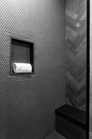 Een badkamer met een structuurwand, een handdoek in een klein raam en een backsplash met een herringbone-tegelpatroon.