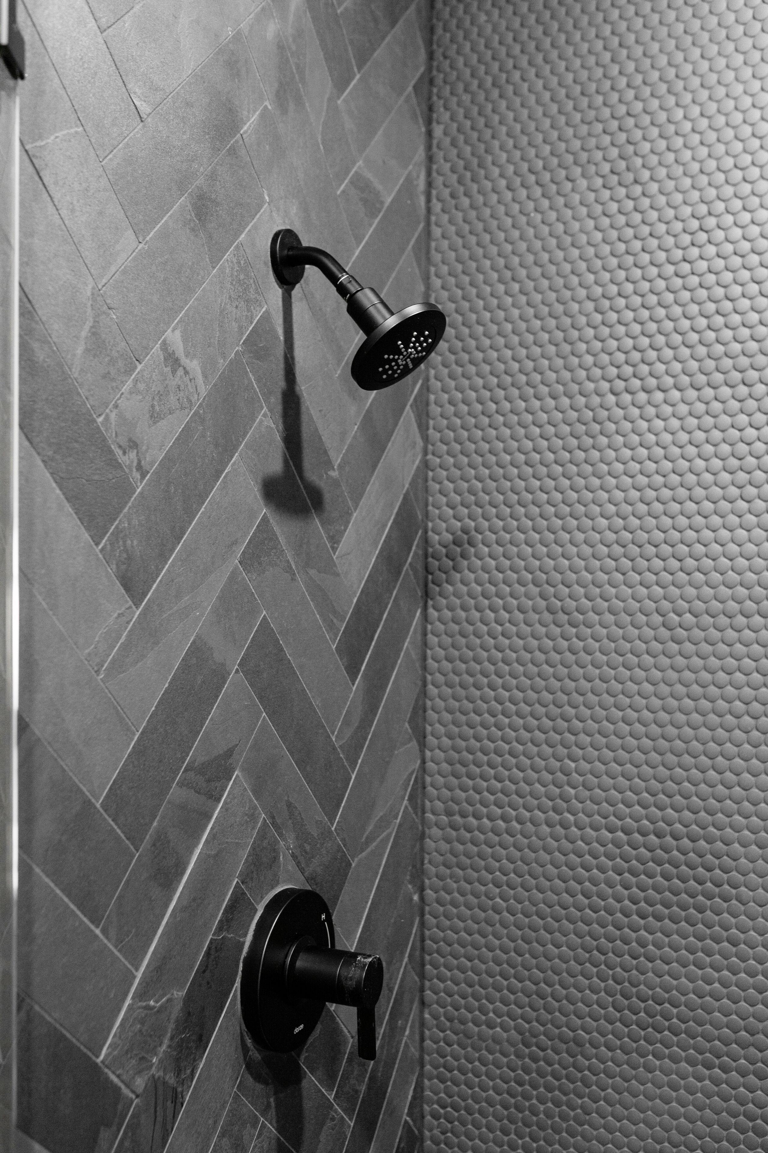 Un espace douche avec un carrelage disposé en motif de chevron et un mur à texture.