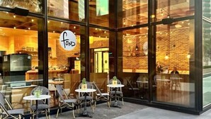 A restaurant with a glass facade, outdoor seating, and a visible menu board. - Mint House Dallas Downtown by Kasa (Dallas)