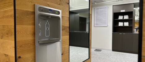 A modern office space with a built-in water dispenser, a wooden wall panel, and a glass partition.