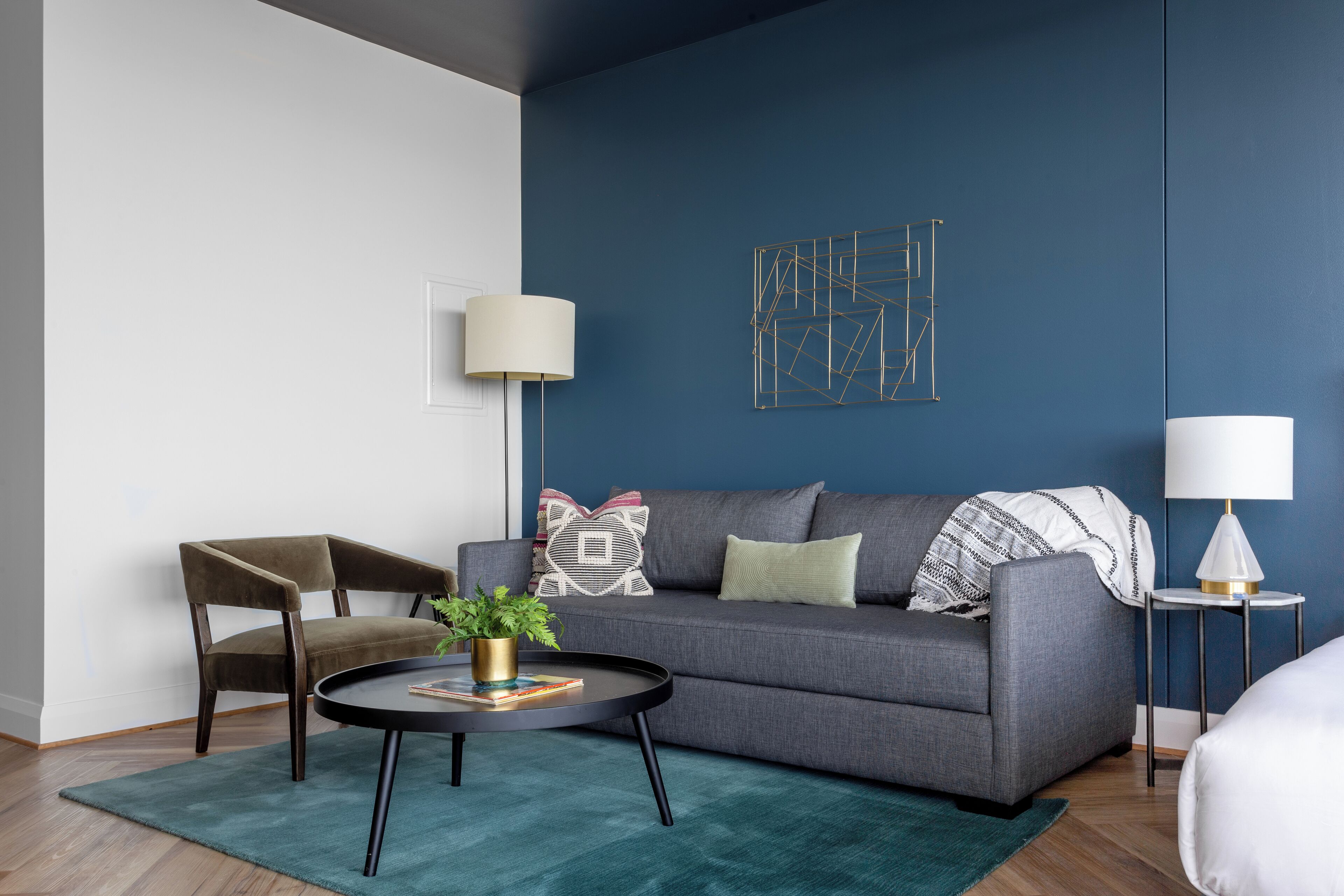 A modern living room with a grey sofa, a round coffee table, and a side table with a lamp.