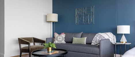 A modern living room with a grey sofa, a round coffee table, and a side table with a lamp.