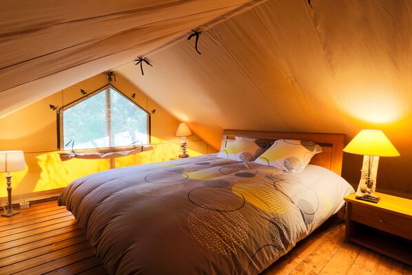 A cozy bedroom with a large bed, a window, and two bedside lamps.