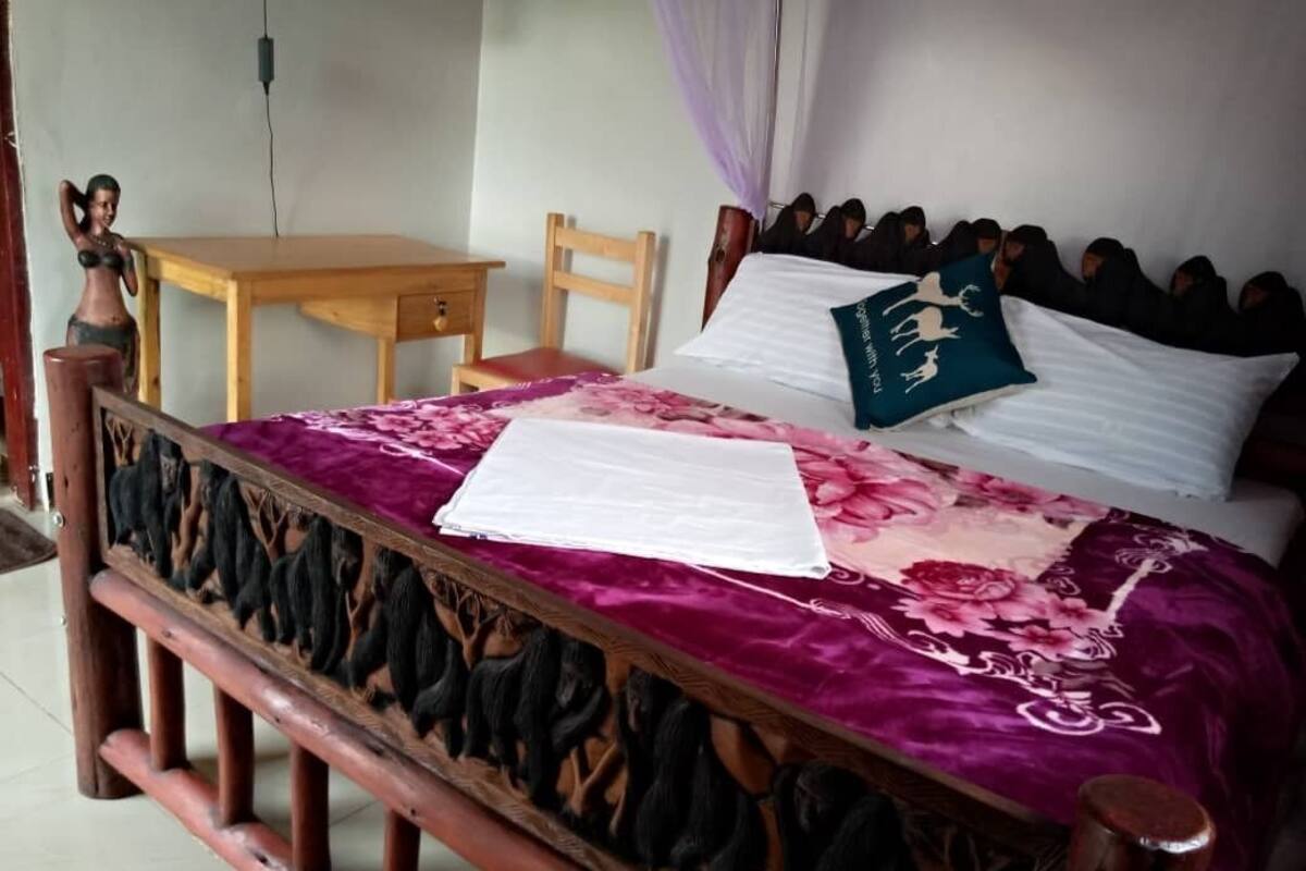A bed with a floral bedspread, a wooden headboard, and a pillow with a logo.