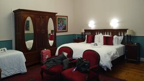 Habitación de hotel con una cama grande, dos mesitas de noche, un armario y un espejo.
