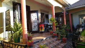 Un espacio al aire libre cubierto con escalones que llevan a una puerta, rodeado de plantas en macetas y una parrilla.