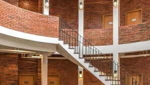 A multi-level atrium with exposed brick walls, white railings, and a central staircase. - Rumanami Residence (Jakarta)