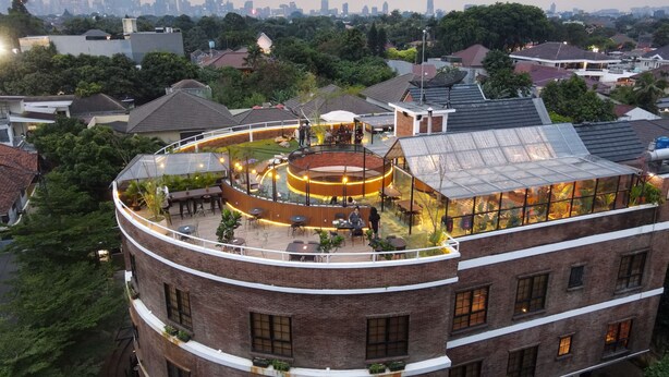A multi-story building with a rooftop terrace featuring outdoor seating and a glass enclosure. - Rumanami Residence (Jakarta)