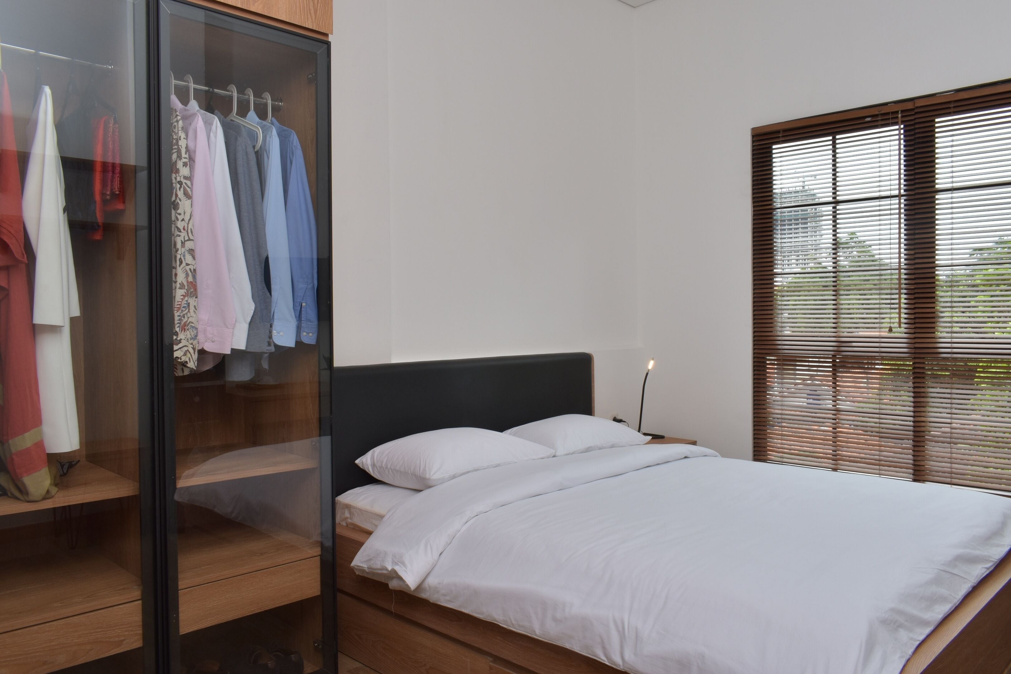 Une chambre à coucher avec un lit, une armoire et une fenêtre équipée de stores.