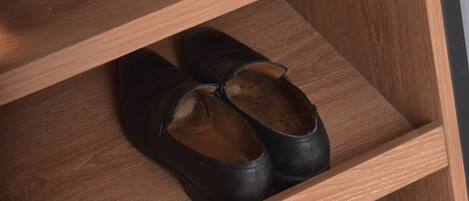 Un zapatero de madera con dos estantes, cada uno sosteniendo un par de zapatos.