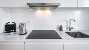 Een moderne keuken met een roestvrijstalen afzuigkap, een waterkoker, een broodrooster en een spoelbak met een kraan.