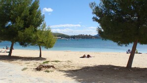Una playa con pavimento de piedra, árboles y vista al mar.