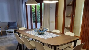 Comedor con una mesa rectangular, seis sillas, dos lámparas colgantes y vistas a zonas verdes al exterior.