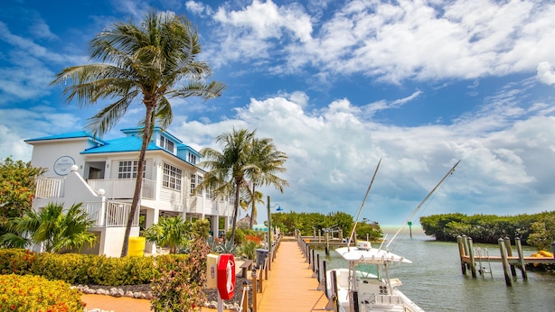 A waterfront property with a dock, boats, and a building with a blue roof. - Oceanfront Views at Ocean Pointe + Pool + Beach & Marina Access, Updated 2BR (Tavernier)