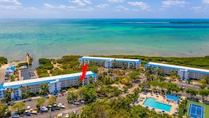 A resort with multiple buildings, a swimming pool, and a view of the ocean. - Oceanfront Views at Ocean Pointe + Pool + Beach & Marina Access, Updated 2BR (Tavernier)