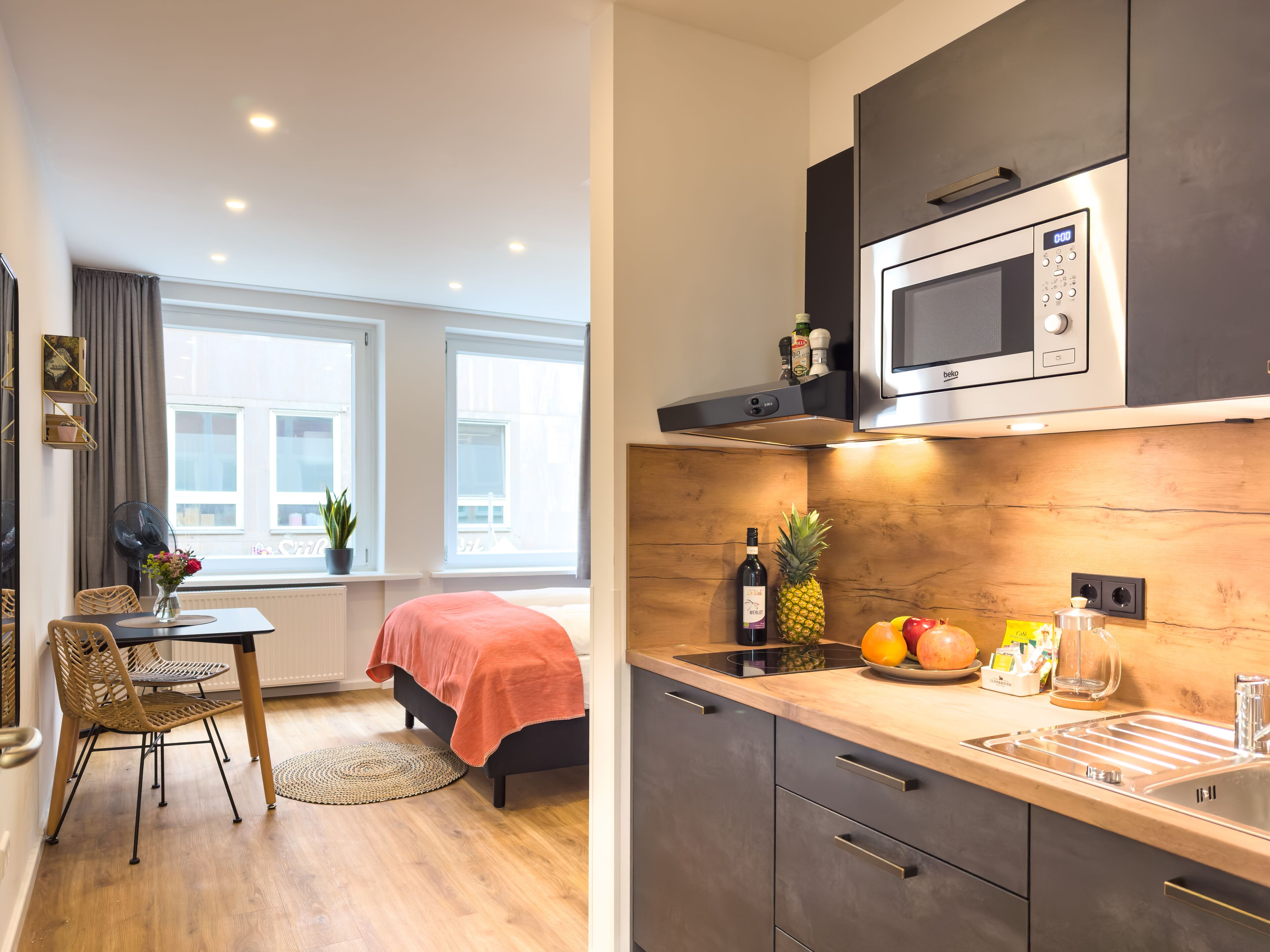 A modern kitchen with a microwave, a sink, and a dining area with a table and chairs.